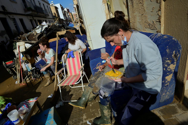 Des femmes assises au milieu des débris et dans la boue, près de Valence en Espagne