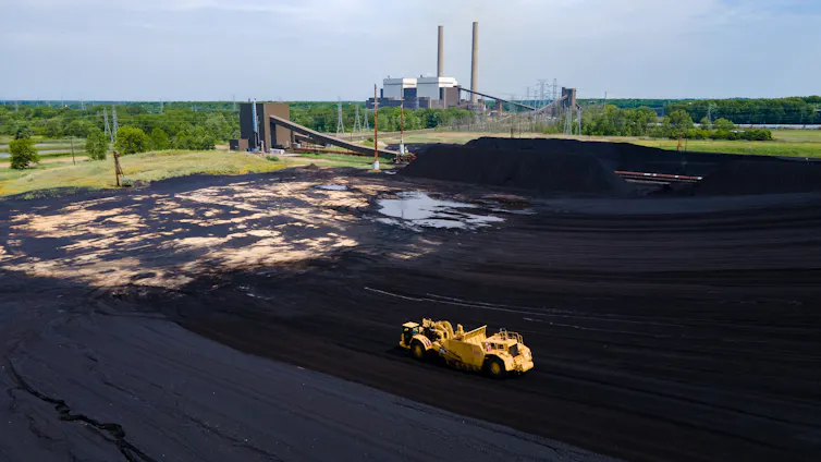 Aerial view of an open-cast coal mine with power plant chimneys in the distance