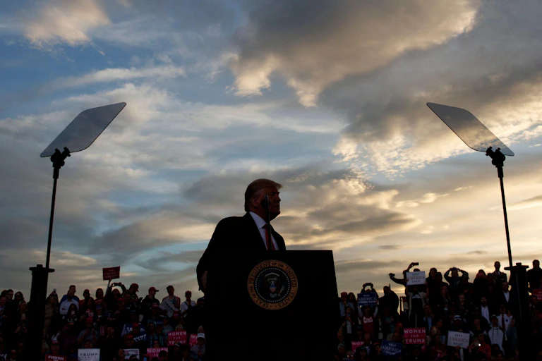 Trump addresses an outdoor rally at dusk.