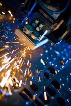 Laser cutting machine creates sparks as it cuts metal