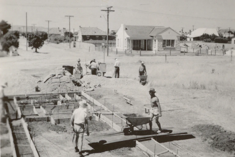 A black and white photograph of people building a house