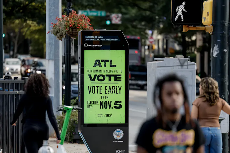 People walk past a billboard encouraging early voting in downtown Atlanta, Georgia.