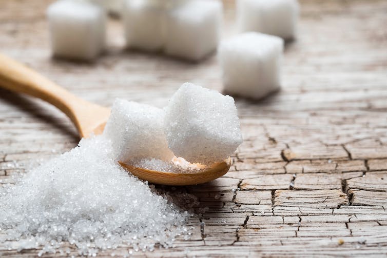 White sugar in wood spoon on wood table