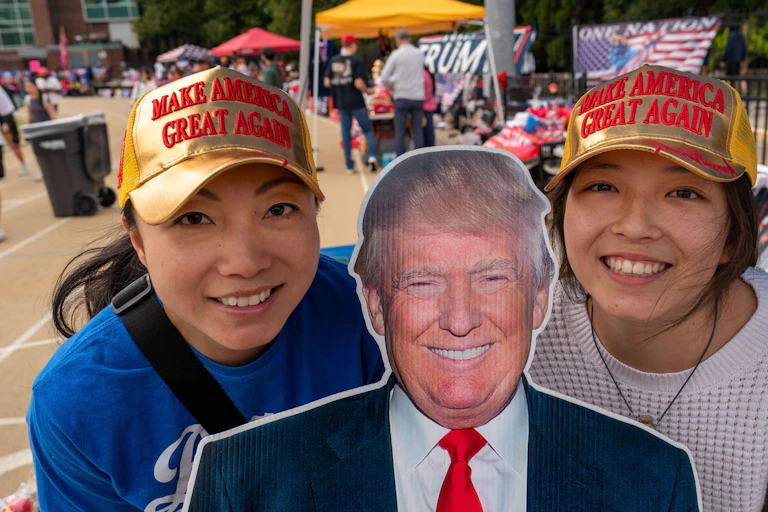 Two young Trump supporters wearing MAGA caps and with a Trump cut-out.