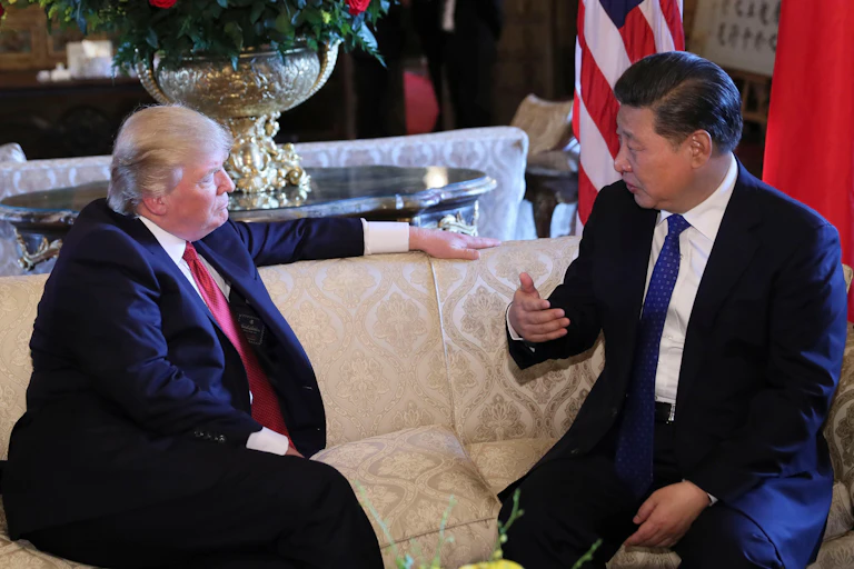 Donald Trump and China's president Xi sit on a sofa talking.