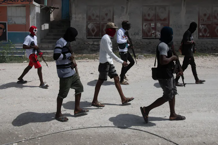 Gang members with guns walk on the streets of Port au Prince in Haiti, July 2024