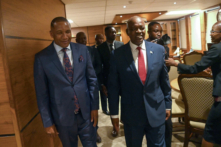 Two men wearing suits and ties walk in an office.