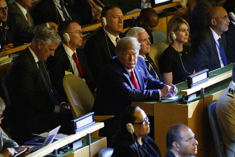 Donald Trump olha para a câmera durante uma reunião da ONU com outras autoridades dos EUA atrás dele.