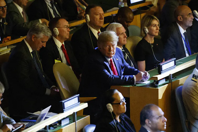 Donald Trump looks toward the camera during a UN meeting with other U.S. officials behind him.