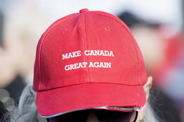Close up of a person wearing a red hat with the words make canada great again