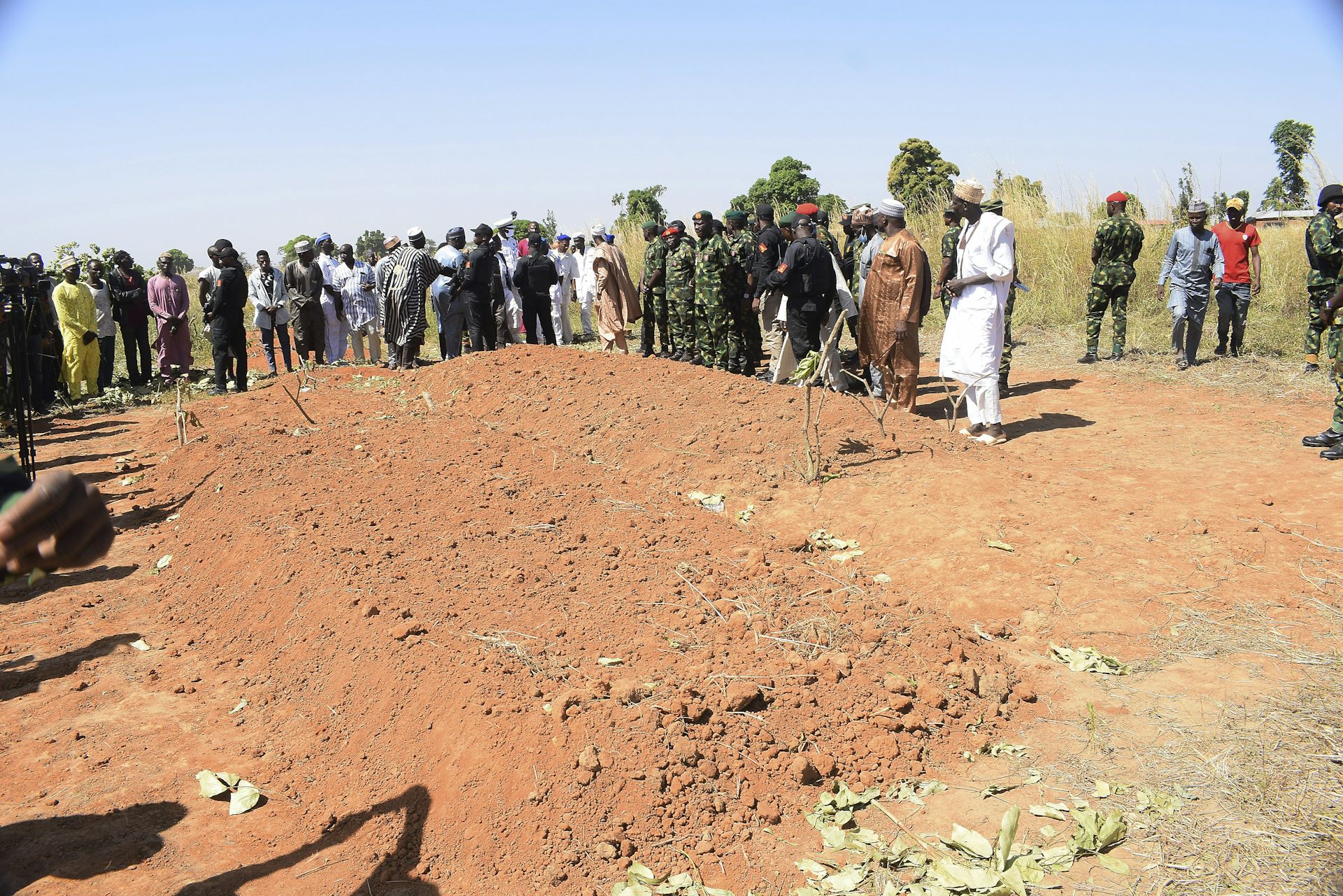 People stand around a large plot of freshly dug dirt.