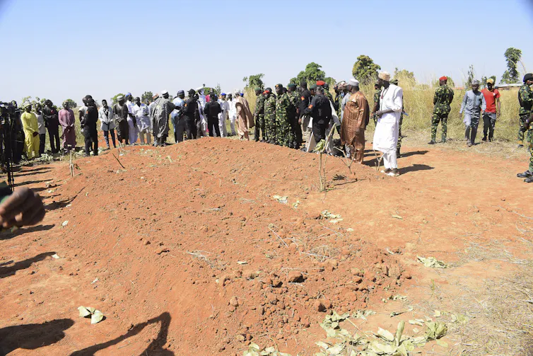 People stand around a large plot of freshly dug dirt.