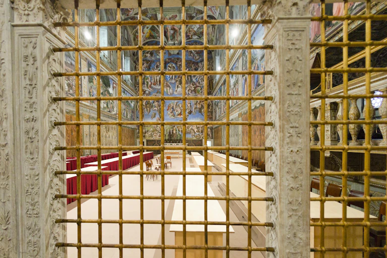 A yellow metal grate blocks off an ornate, narrow room several stories high with a mural along the walls.