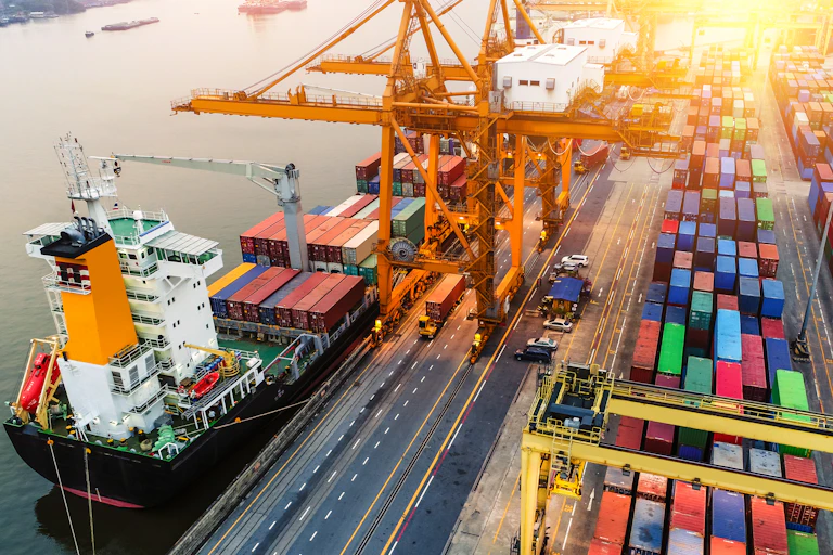 Logistics and transportation of Container Cargo ship and Cargo plane with working crane bridge in shipyard at sunrise