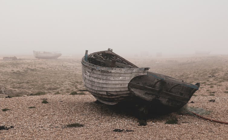 Wrecked fishing boats on the Dungeness shore surrounded by mist