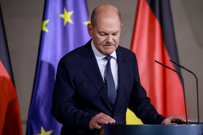 Olaf Scholz stands at a podium in front of German and EU flags