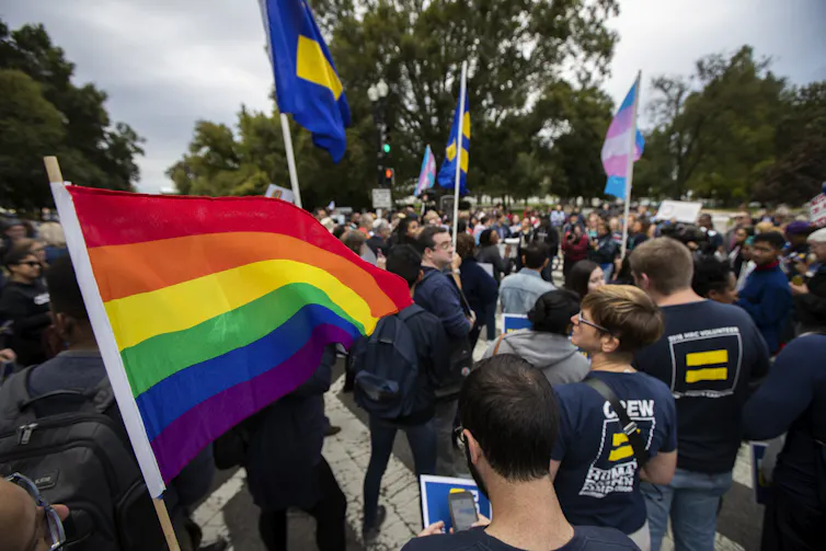 Crowd marches with rainbow flags