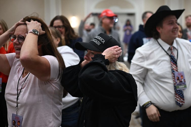 Happy people in a crowd holding their heads in disbelief or excitement.