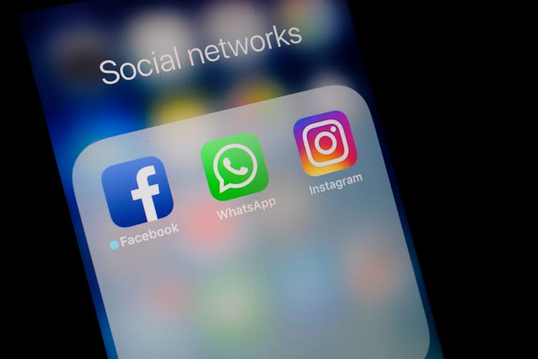 Logos of Facebook, WhatsApp and Instagram on phone screen.