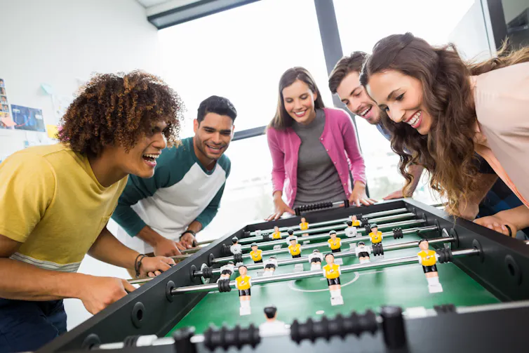Young men and women playing table soccer