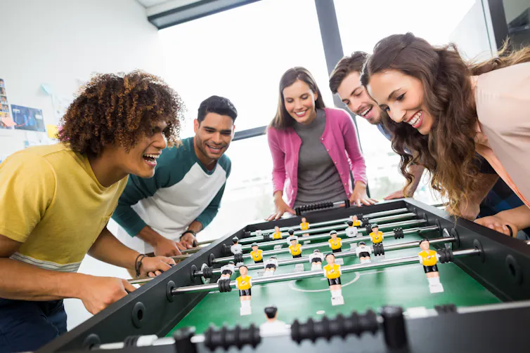 Young men and women playing table soccer