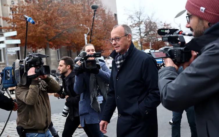 Friedrich Merz walking past reporters in the street