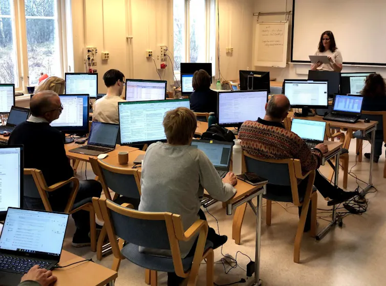 Room of scientists on computers reading scientific articles