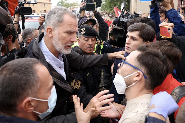 Un hombre de barba habla con varios jóvenes rodeado de fuerzas de seguridad.