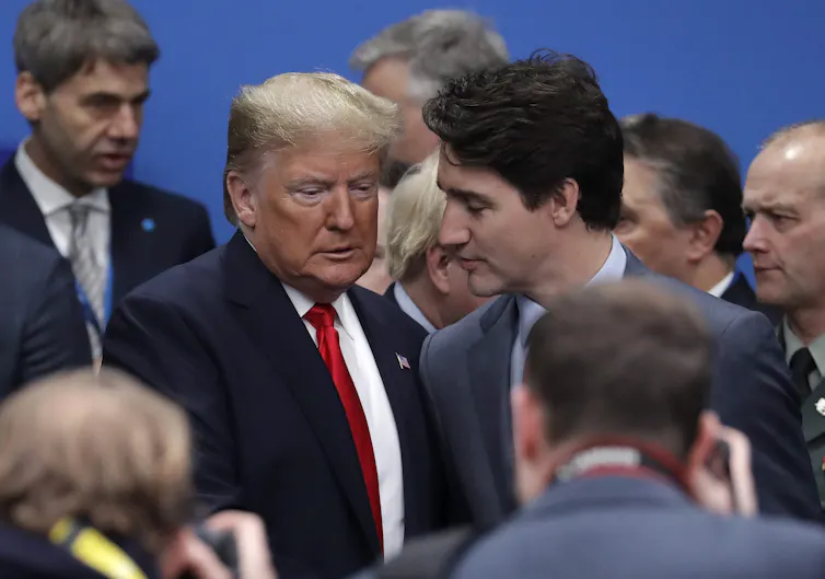 An older man with greyish-blond hair in a conversation with a younger man with dark hair.