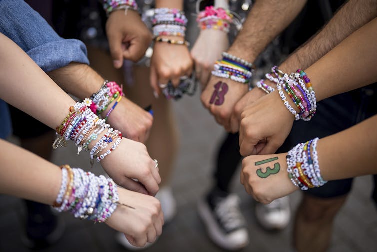 Close-up of beaded bracelets stacked on people's arms