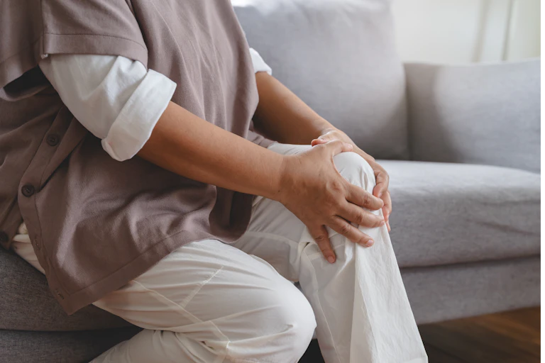A woman sitting on a couch clutching her knee.