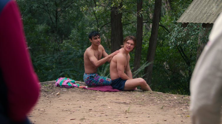 Two men sit on a cliff.