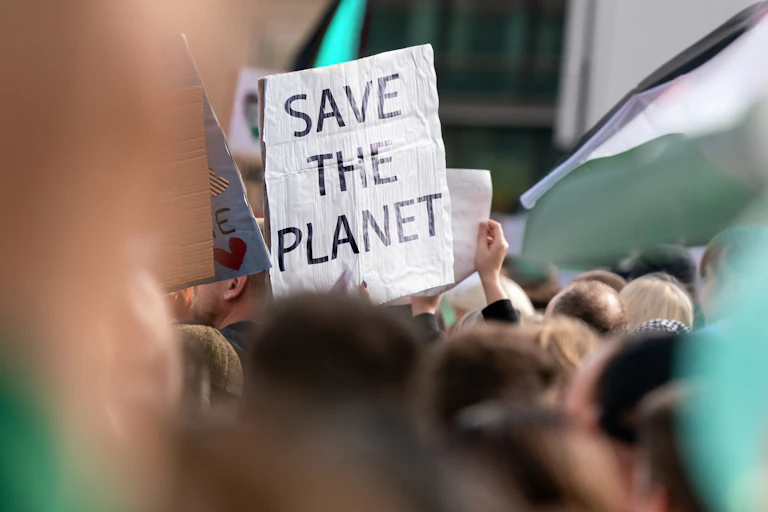 People holding up posters. One says 'save the planet'