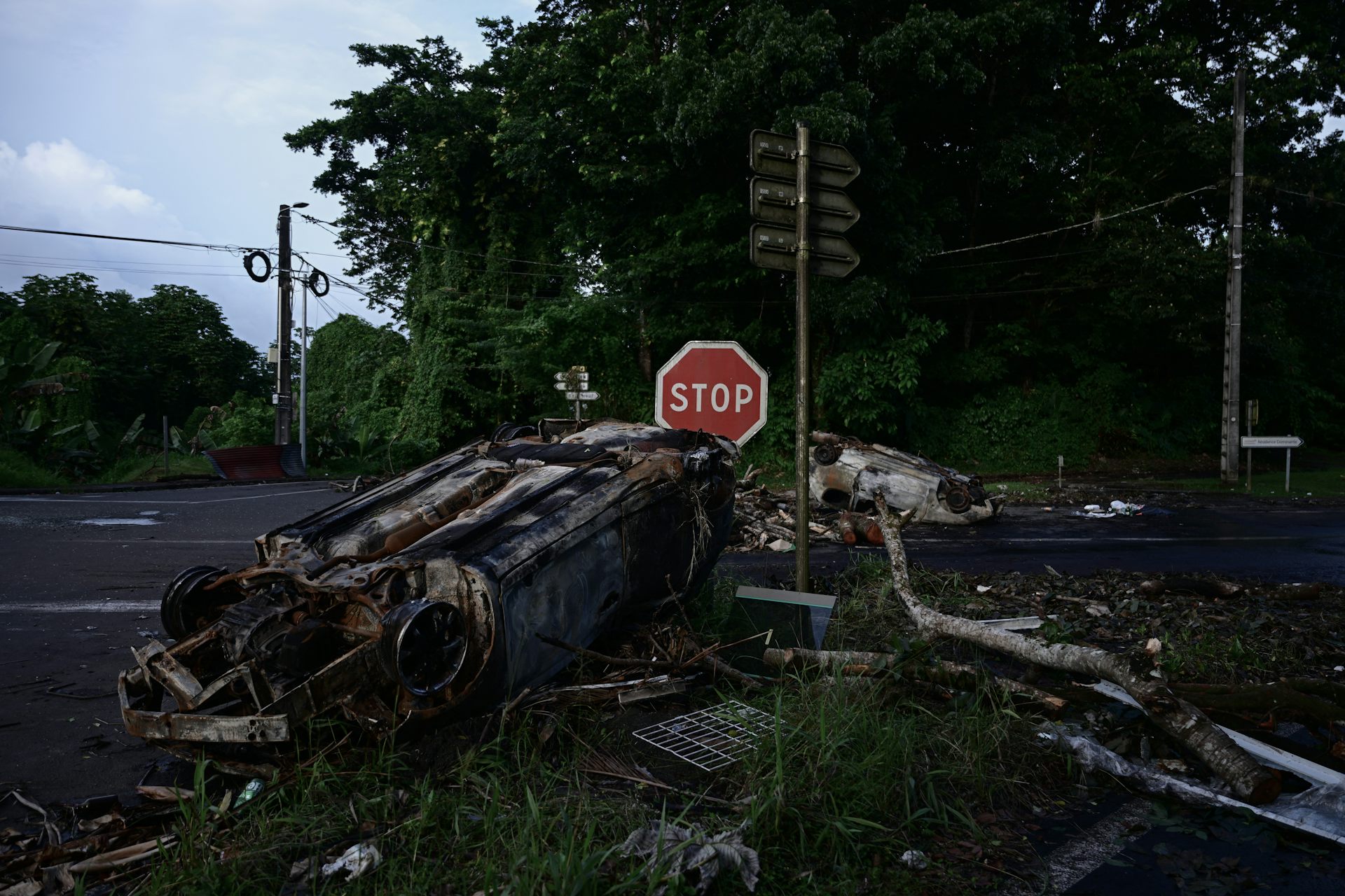 Les épaves de voitures incendiées pendant la nuit sont visibles sur une route de Fort-de-France, dans l’île française de la Martinique, le 13 octobre 2024, dans un contexte d’émeutes liées à la hausse des prix