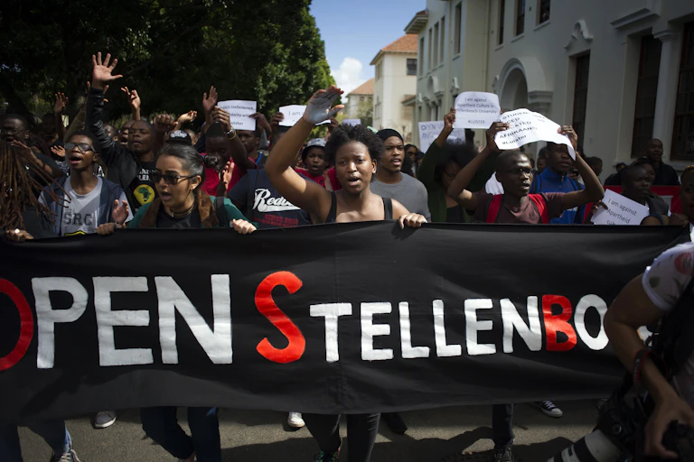 A group of protesters holding a banner that reads Open Stellenbosch. Others are holding placards calling for Afrikaans to be removed as a teaching language
