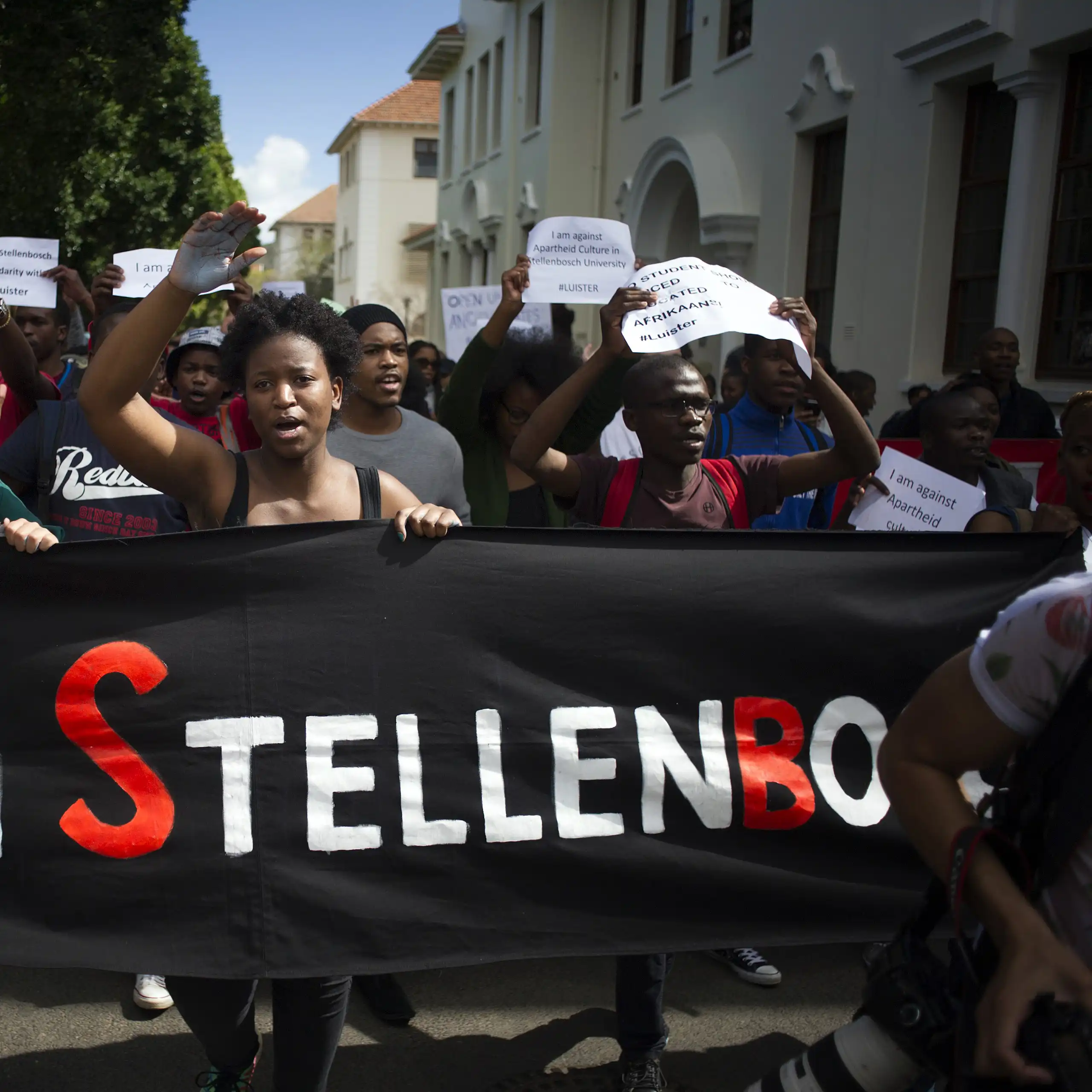 A group of protesters holding a banner that reads Open Stellenbosch. Others are holding placards calling for Afrikaans to be removed as a teaching language