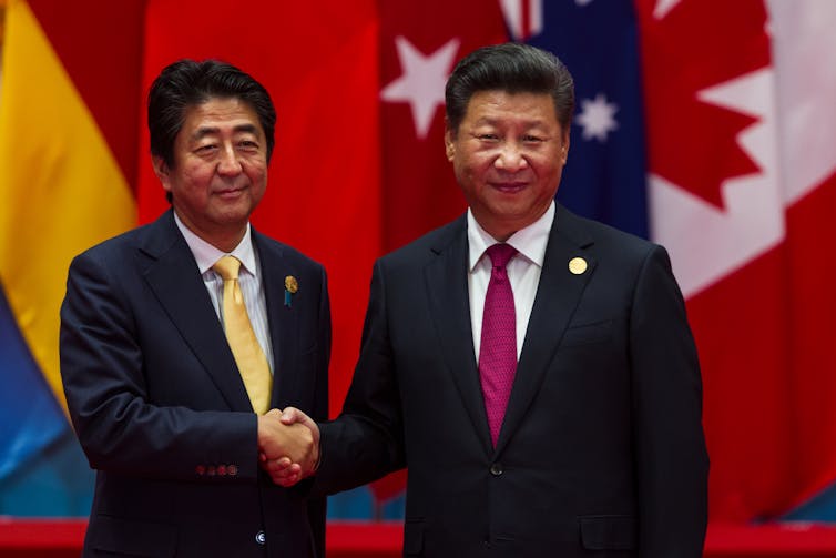 China's president, Xi Jinping, shaking hands with Shinzo Abe.