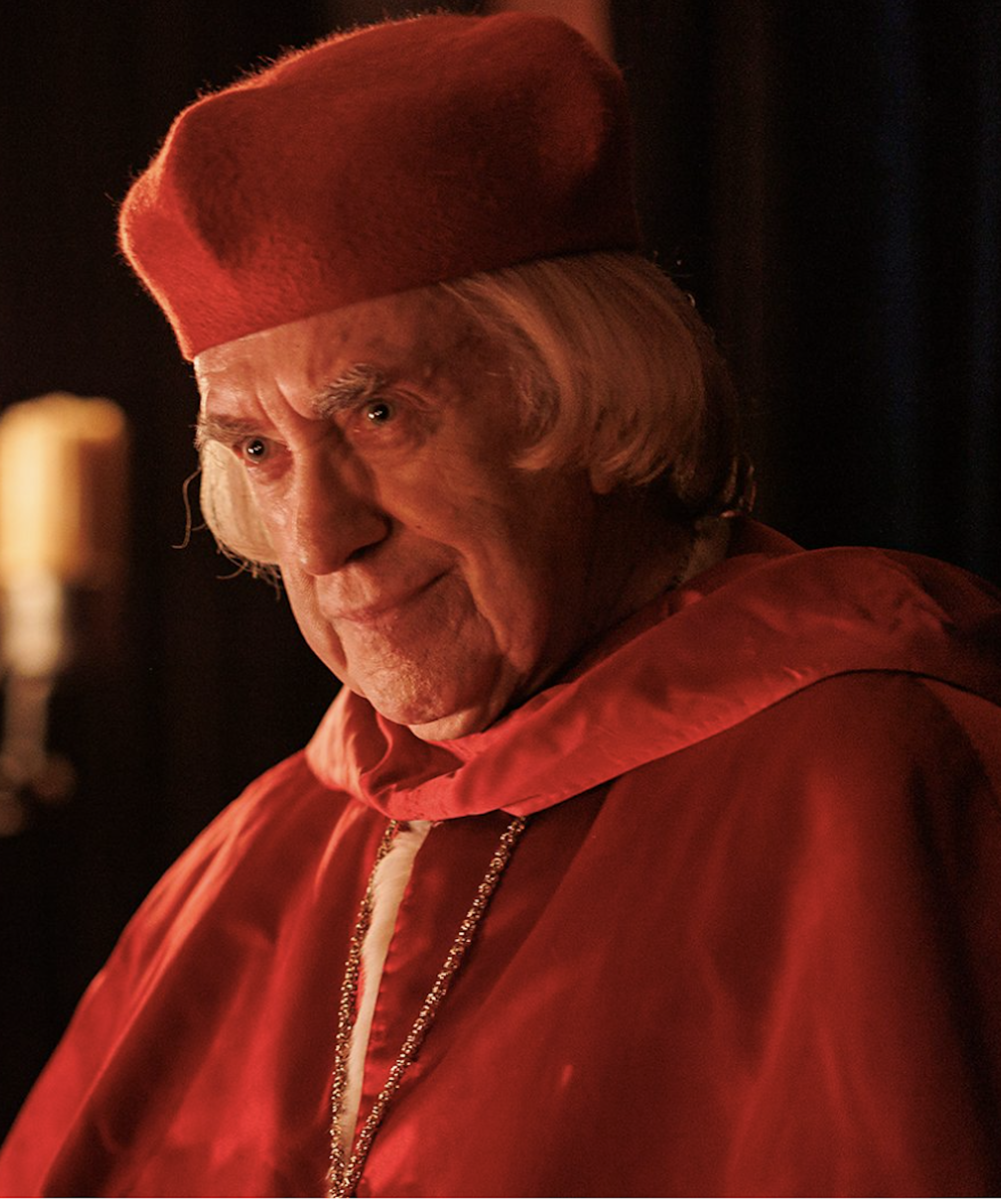 A Tudor era man dressed in the opulent red robes of a cardinal.