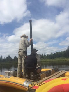 three people on rubber boat with rod going through the middle.