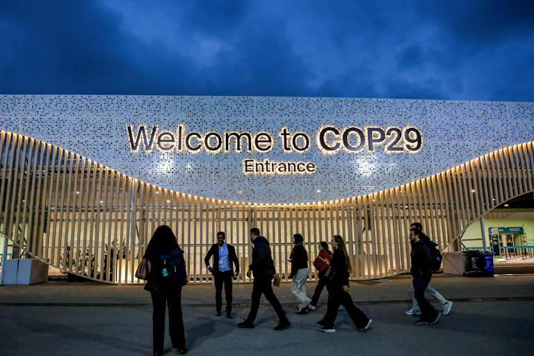 People walk past large 'welcome to Cop29' sign