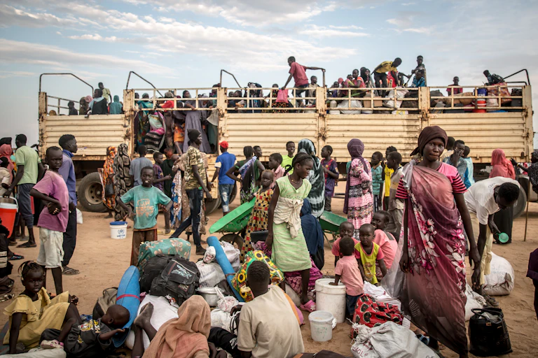 People get off a large truck, carrying bundles and buckets