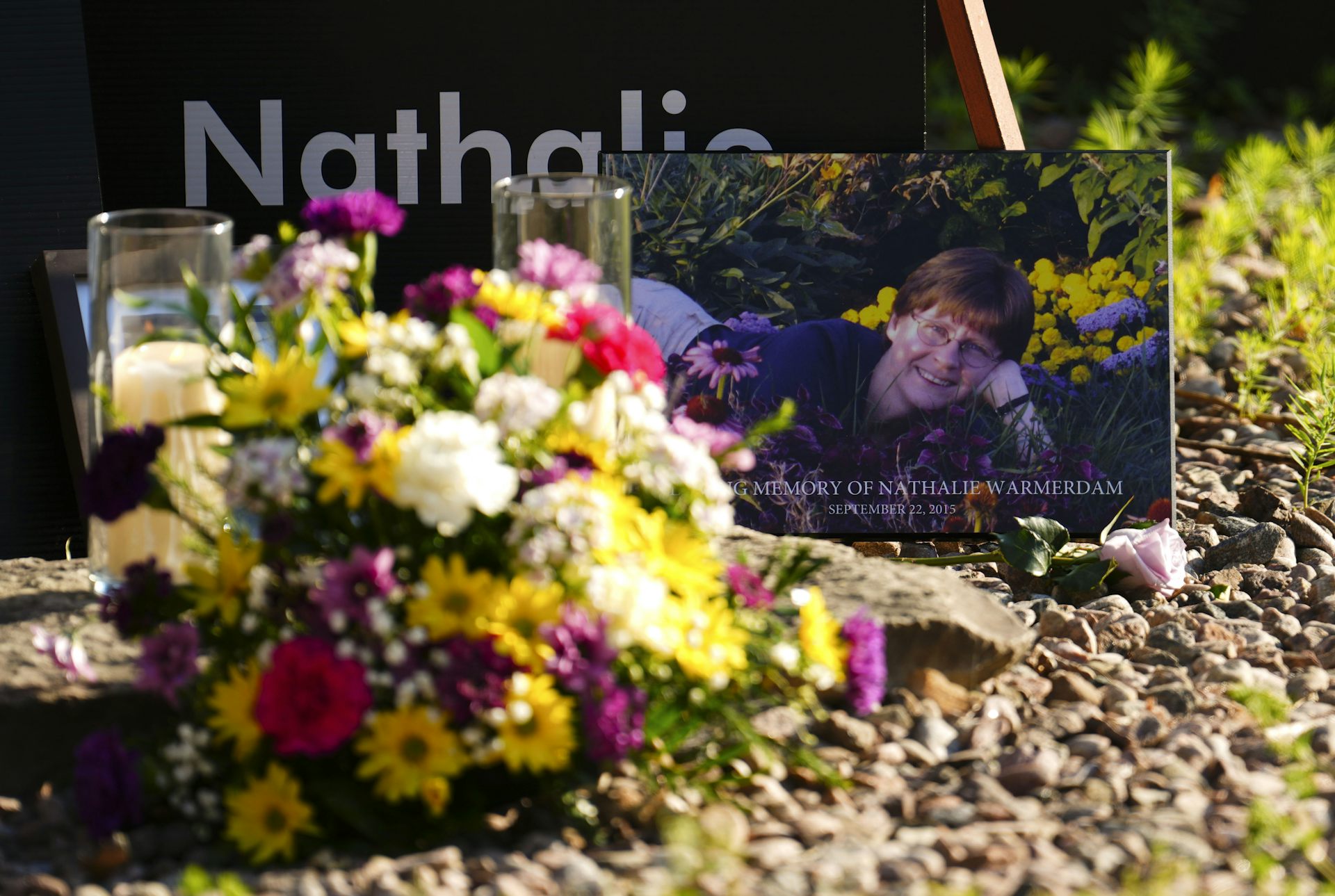 A photograph of a smiling woman with a bouquet of flowers in front of it.