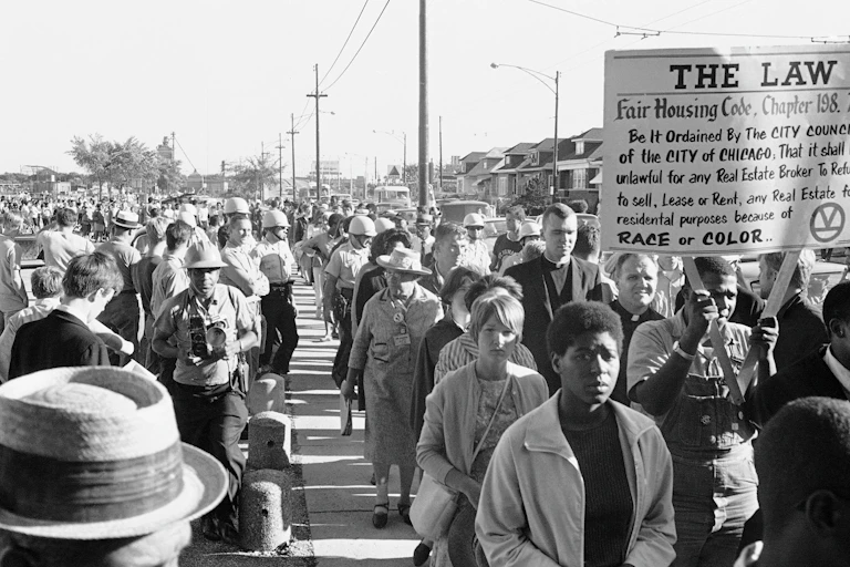 Hundreds of protestors walk on a street.