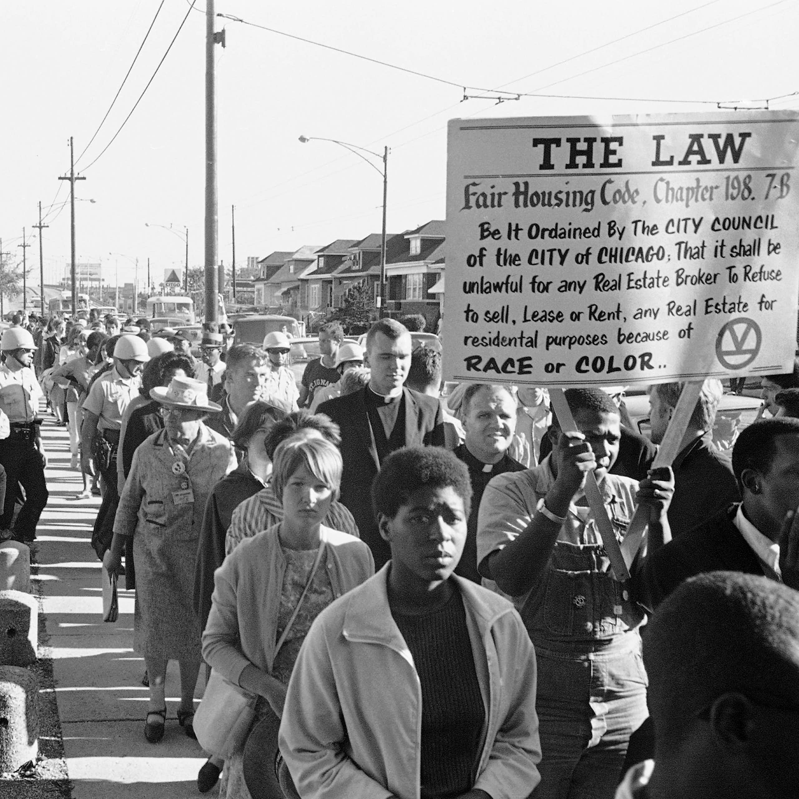 Hundreds of protestors walk on a street.