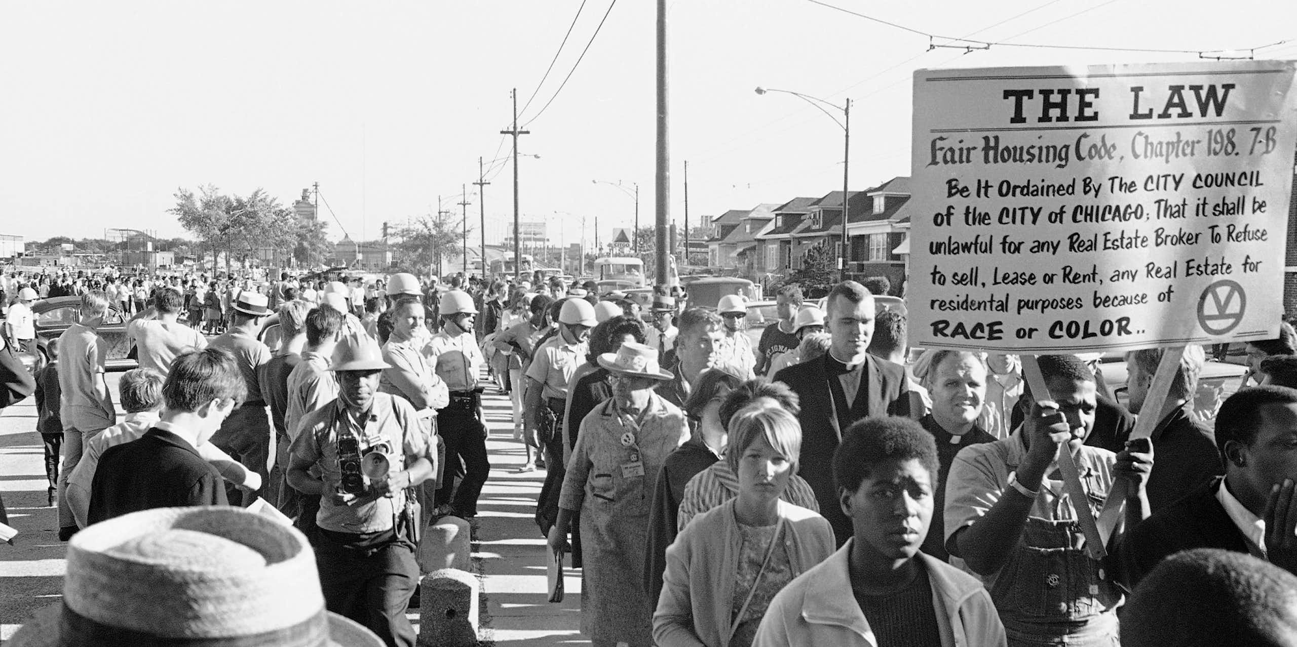 Hundreds of protestors walk on a street.