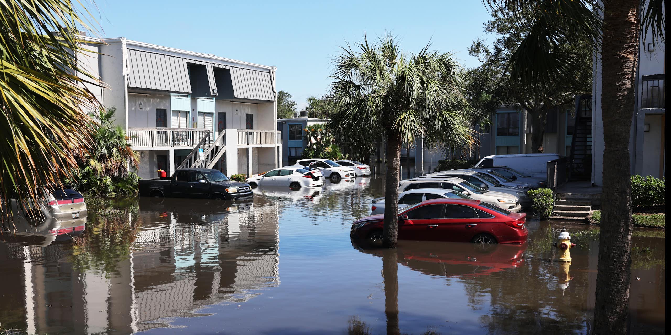 Cars parked outdoors at an apartment complex, submerged up to their bumpers