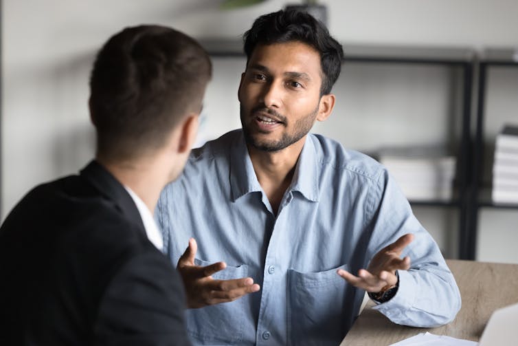 Two men in business attire having a conversation while seated at a table