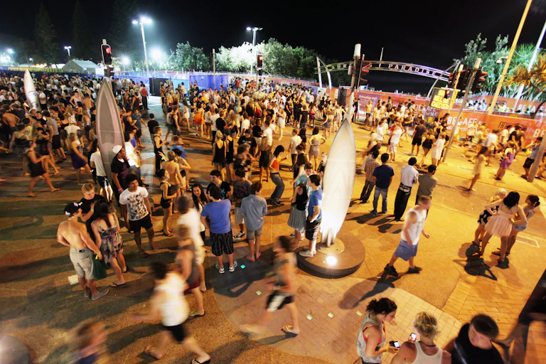 Young people at night time at Surfers Paradise. Event barricades are set up behind them.