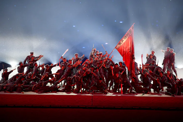 Chinese workers dancing, waving a red flag.