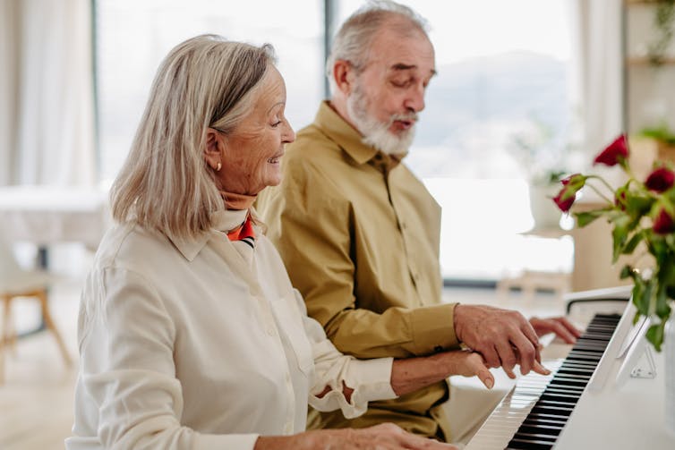 An elderly couple at a piano.